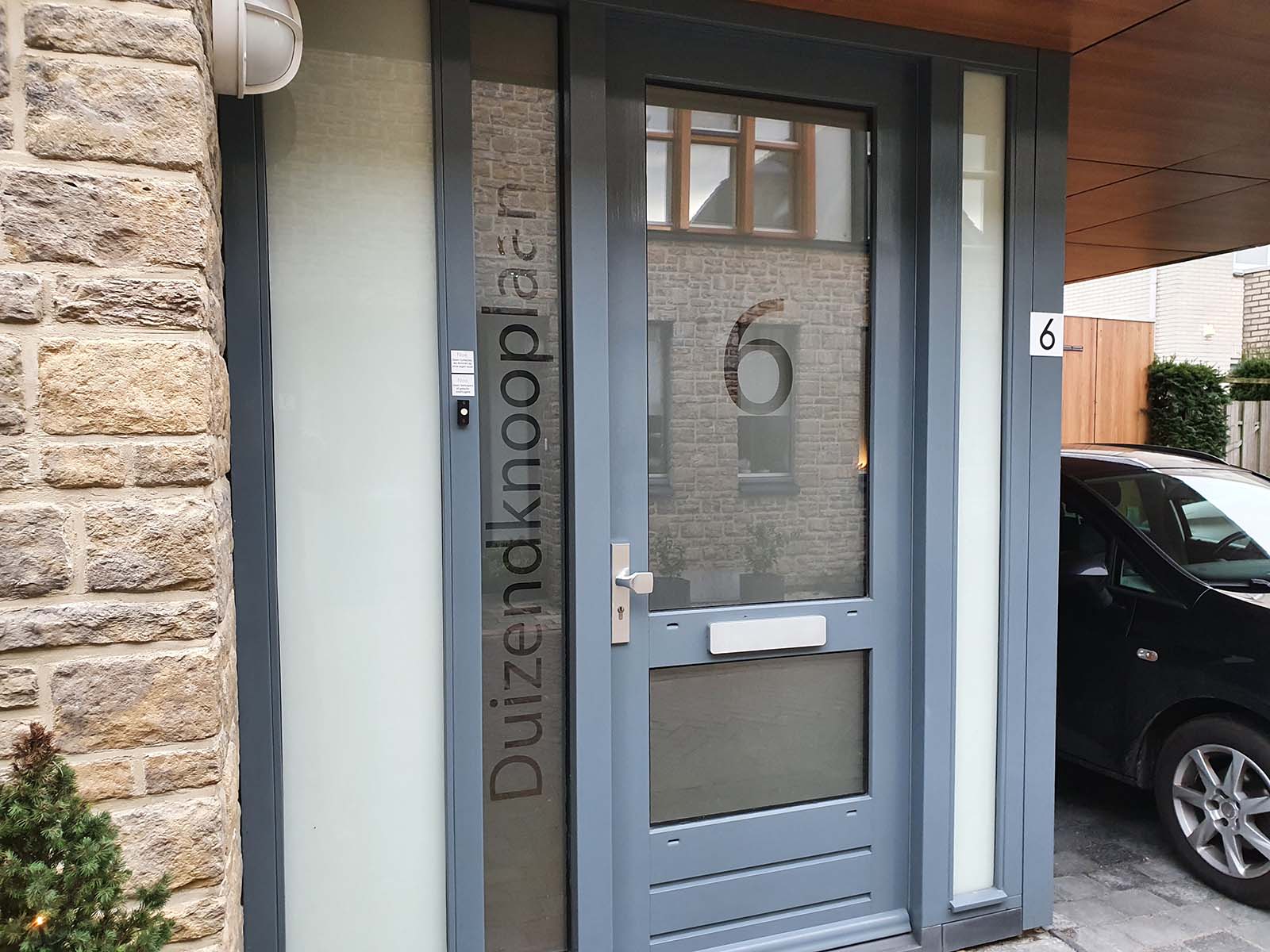 Op maat gemaakte raamfolie voor de voordeur met huisnummer en familienaam