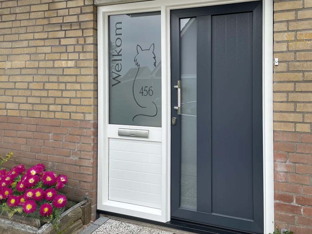 Zelfklevende raamfolie op een voordeur met uitgesneden kat-illustratie met tekst "Welkom" en huisnummer.