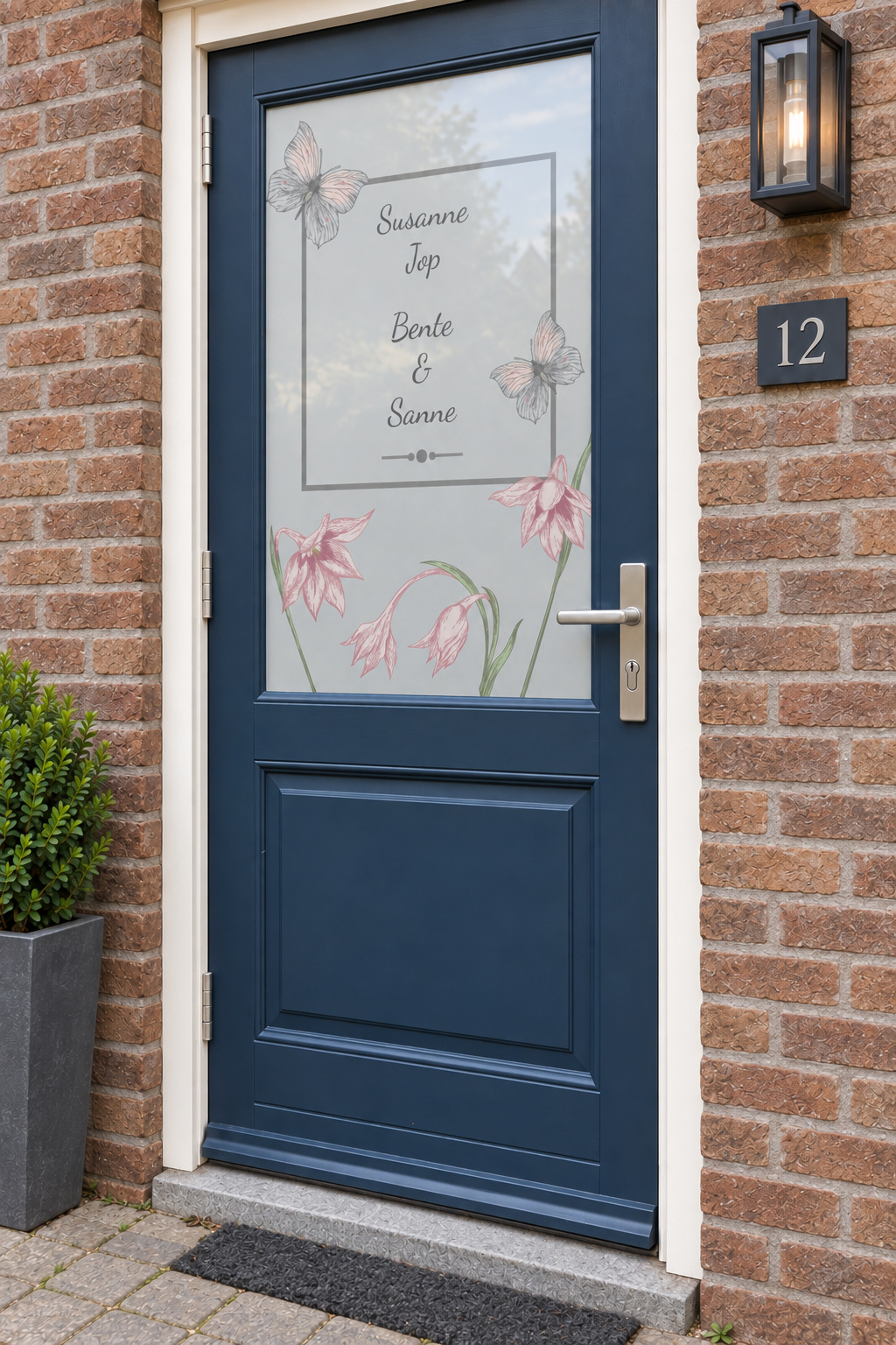 Voordeur met bedrukte matglasfolie bloemen en vlinders met namen, licht schuin aanzicht.