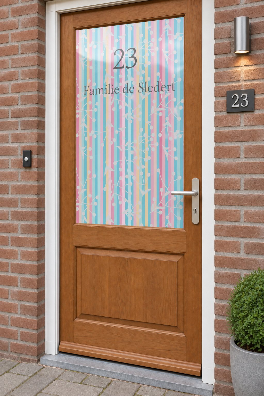Voordeur met bedrukte matglasfolie gekleurde strepen, naam en huisnr, licht schuin aanzicht.