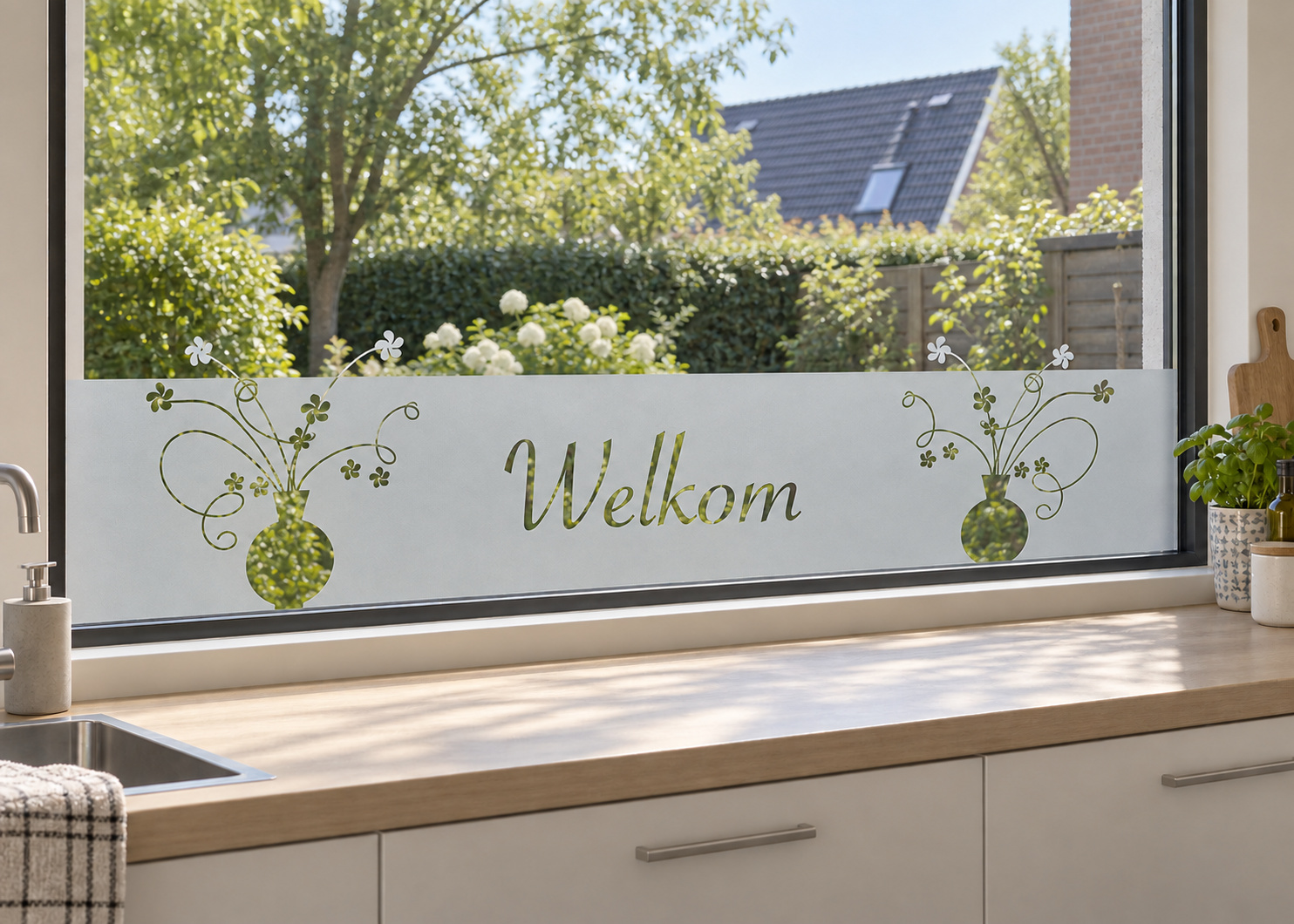Raamfolie bloemen in vaas (RFH034) als horizontale raamfolie boven het aanrecht in een keukenraam, met matte folie en doorkijk naar de tuin.