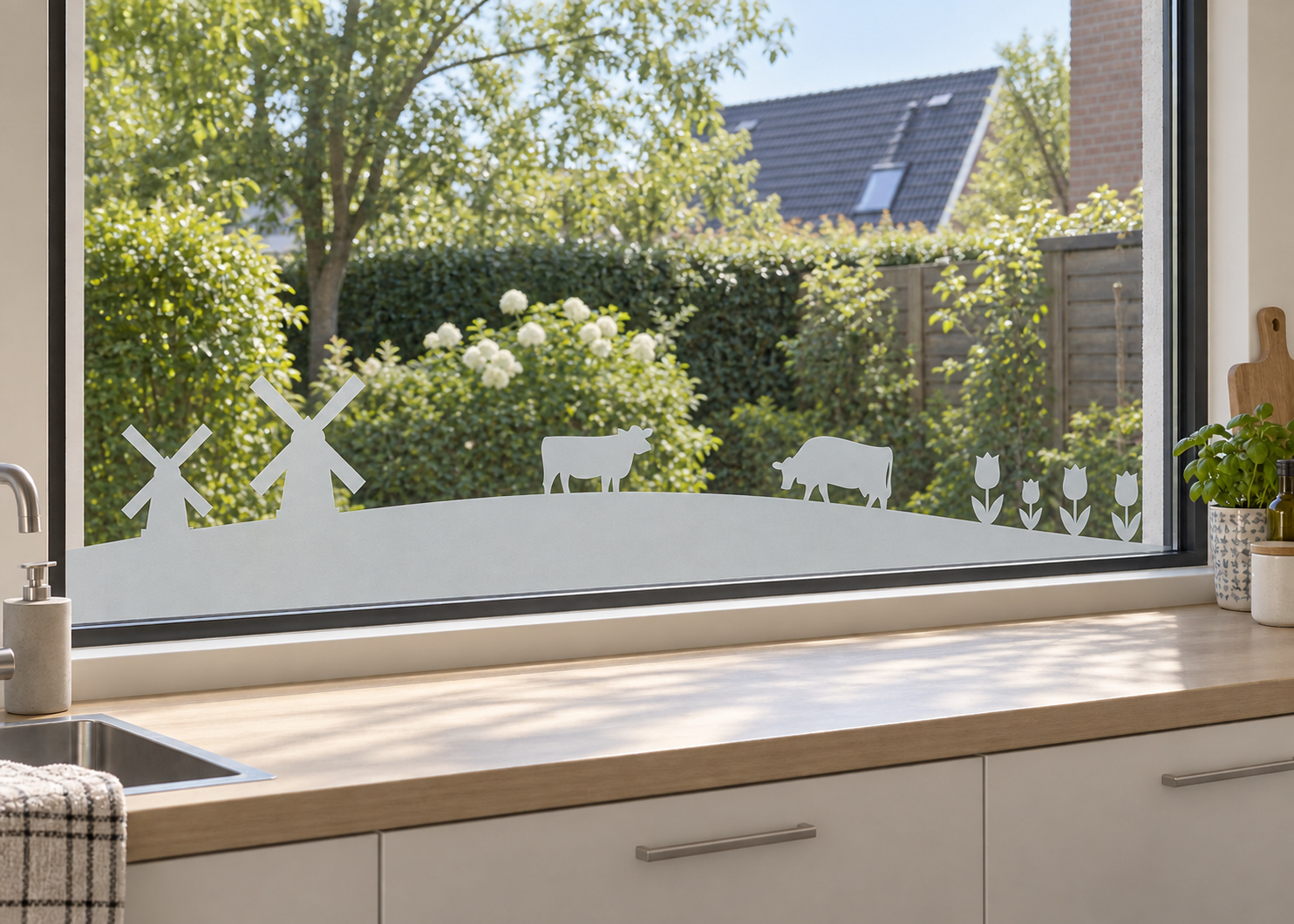 Raamfolie Hollands landschap (RFH012) als horizontale raamfolie boven het aanrecht in een keukenraam, met matte folie en doorkijk naar de tuin.