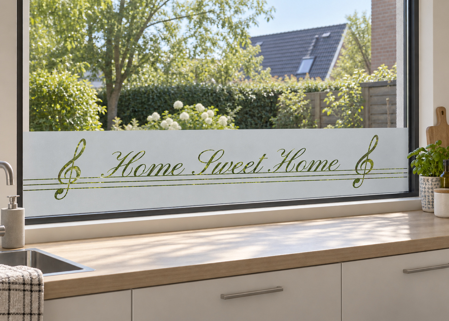 Raamfolie met muzieknootjes - Home Sweet Home (RFH033) als horizontale raamfolie boven het aanrecht in een keukenraam, met matte folie en doorkijk naar de tuin.