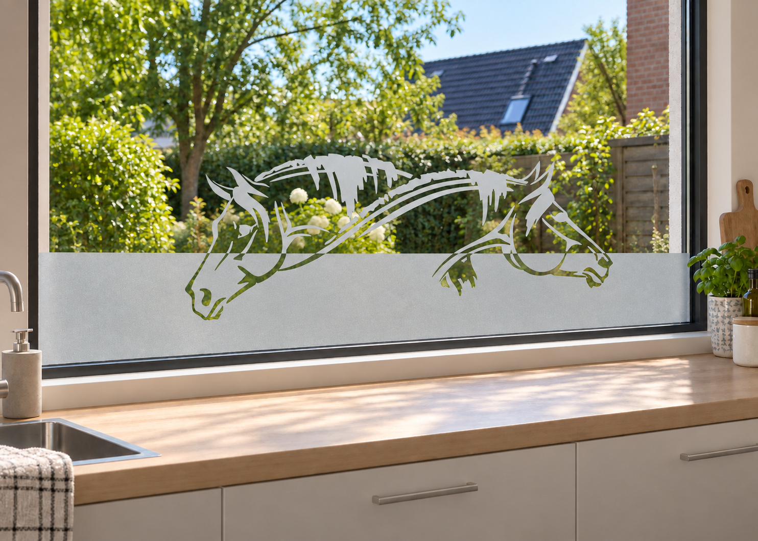 Raamfolie paarden (RFH020) als horizontale raamfolie boven het aanrecht in een keukenraam, met matte folie en doorkijk naar de tuin.