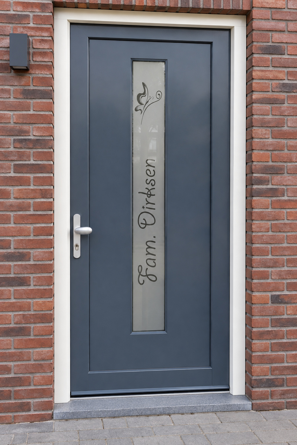 Verticale raamfolie met een sierlijke vlinder en een naam in een smalle, verticale glasstrook in de voordeur.