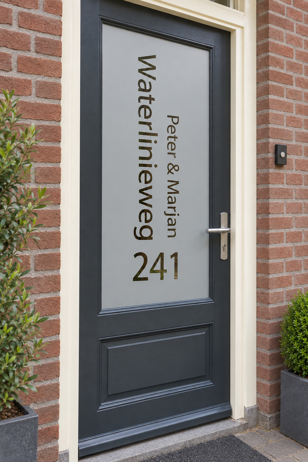 Schuin aanzicht van een Nederlandse voordeur met een verticale straatnaam, namen en huisnummer in raamfolie straatnaam en namen.