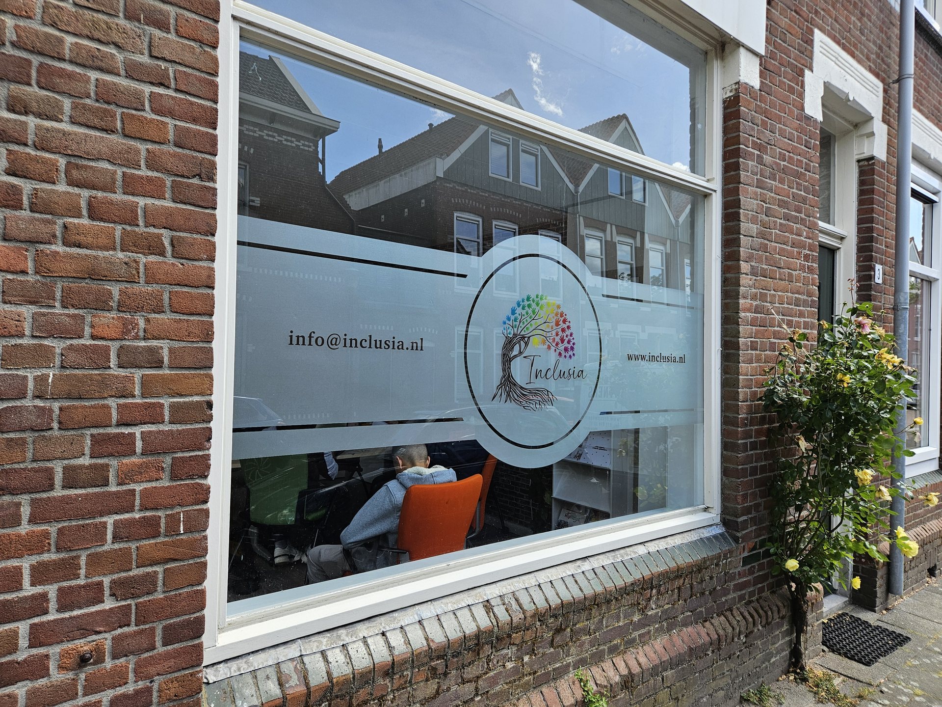Raam aan de straatzijde met een gekleurd logo op matte folie en uitgesneden ronde elementen.